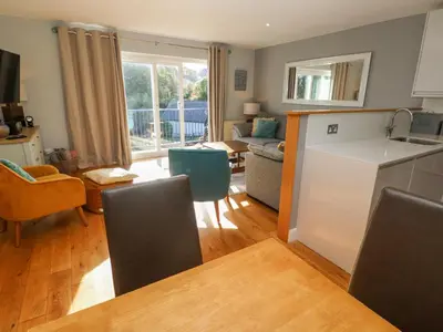 a kitchen and living room with a table and chairs at Sea Dream in Falmouth