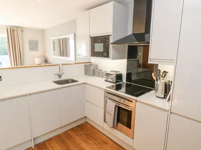 a white kitchen with white cabinets and a sink at Sea Dream in Falmouth