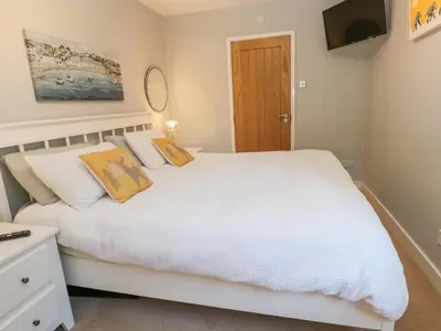 a bedroom with a white bed and a flat screen tv at Sea Dream in Falmouth