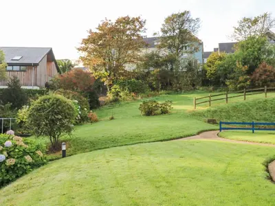a grassy yard with a fence and a house at Sea Dream in Falmouth