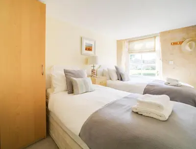 a bedroom with two beds with white sheets and a window at Turtle Cottage in Charlestown
