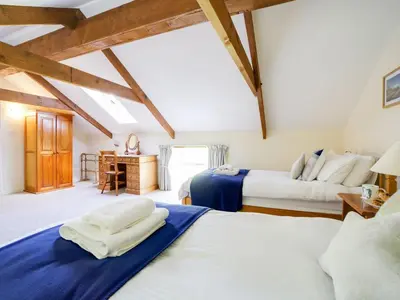 two beds in a room with wooden beams at Turtle Cottage in Charlestown