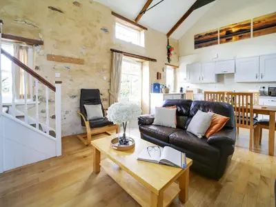 a living room with a leather couch and a table at Turtle Cottage in Charlestown