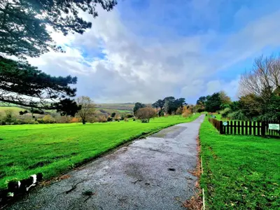 a wet road in a field with a fence at JL Cornwall Newquay Caravan in Newquay