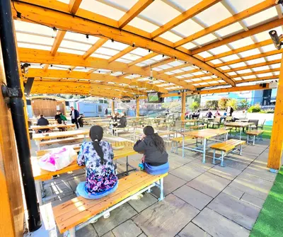 two people sitting on a bench under a pavilion at JL Cornwall Newquay Caravan in Newquay