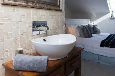 a bathroom with a white sink and a bed at Little Bream - pretty cosy cottage, sea views, walk to the beach in Mawnan Smith