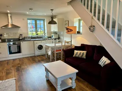 a living room with a couch and a table at Little Bream - pretty cosy cottage, sea views, walk to the beach in Mawnan Smith