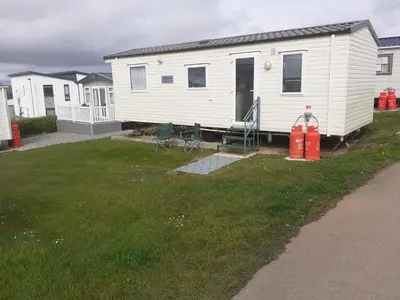 a white mobile home with chairs and a fire hydrant at PerranporthCaravan 2bedroom Tv GasFire in Perranporth