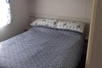 a bedroom with a bed with a blue and white comforter at PerranporthCaravan 2bedroom Tv GasFire in Perranporth
