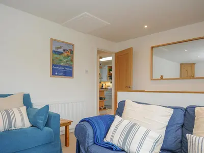 a living room with a blue couch and a mirror at Seamay in Wadebridge