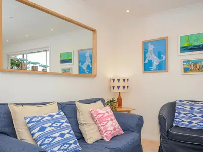 a living room with a blue couch and a mirror at Seamay in Wadebridge