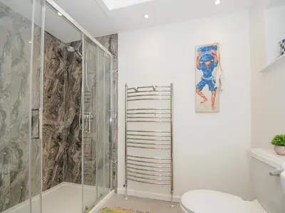 a white bathroom with a shower and a toilet at Seamay in Wadebridge