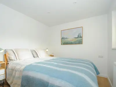 a white bedroom with a bed with a blue blanket at Seamay in Wadebridge