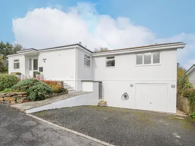 a white house with a garage and a driveway at Seamay in Wadebridge