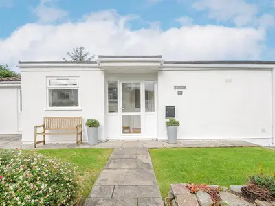 a white house with a bench in a yard at Seamay in Wadebridge