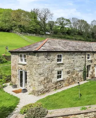 a stone house in a field with grass at Coach House St Wenn in Bodmin