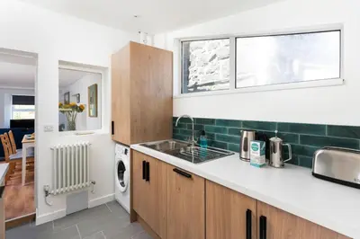 a kitchen with a sink and a washing machine at Gwel Porth - St Ives - Sea Views in St Ives