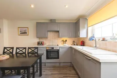 a kitchen with gray cabinets and a table and a sink at Newquay - Atlantic Lodge - 10 - Pets - Pools - Gym in Newquay