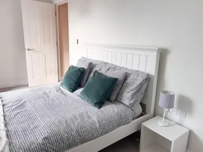 a white bed with green pillows in a bedroom at Waterside apartment, central Falmouth, Vi-spring king bed, gated parking in Falmouth