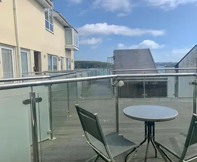 a balcony with a table and chairs on a building at Waterside apartment, central Falmouth, Vi-spring king bed, gated parking in Falmouth