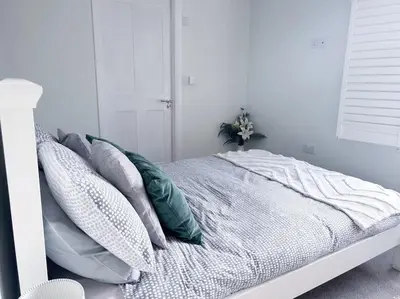 a white bedroom with a bed with pillows at Waterside apartment, central Falmouth, Vi-spring king bed, gated parking in Falmouth