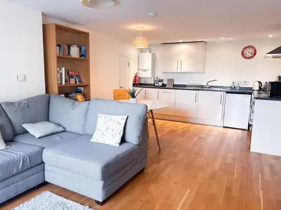 a living room with a couch and a kitchen at Waterside apartment, central Falmouth, Vi-spring king bed, gated parking in Falmouth