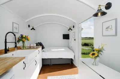 a kitchen with a bed in a tiny house at Shepherds Hut at Chenhall Farm in Helston