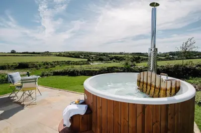 a jacuzzi tub with a view of the countryside at Shepherds Hut at Chenhall Farm in Helston