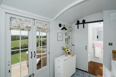 a room with white walls and a door with a window at Shepherds Hut at Chenhall Farm in Helston