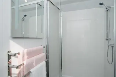 a bathroom with a glass shower with pink towels at Shepherds Hut at Chenhall Farm in Helston