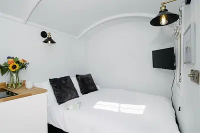 a bedroom with a white bed with a vase of flowers at Shepherds Hut at Chenhall Farm in Helston