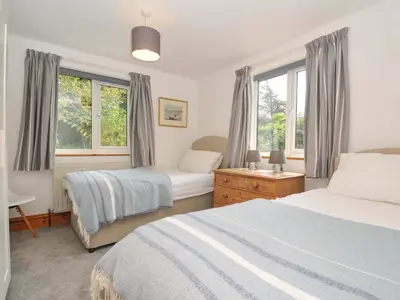 a bedroom with two beds and two windows at Seaworthy in Wadebridge