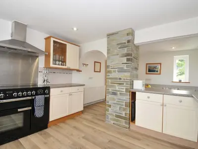 a kitchen with a stove and a stone wall at Seaworthy in Wadebridge