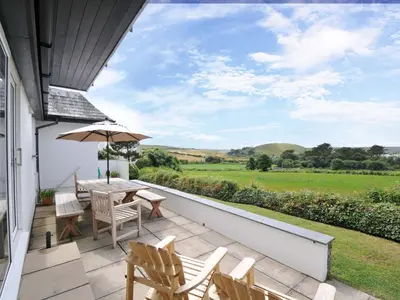 a patio with chairs and a table and an umbrella at Seaworthy in Wadebridge