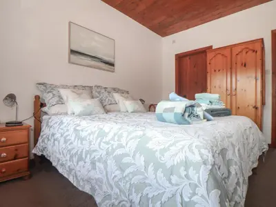 a bedroom with a large bed with a wooden headboard at Court Cottage in Looe