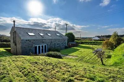 an old stone house with skylights on a green field at Finest Retreats - Trennal Barn in Germoe