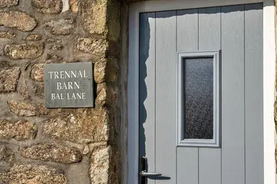 a sign on a stone wall next to a door at Finest Retreats - Trennal Barn in Germoe