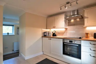 a kitchen with white cabinets and a stove at Finest Retreats - Trennal Barn in Germoe