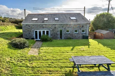a stone house with a picnic table in front of it at Finest Retreats - Trennal Barn in Germoe