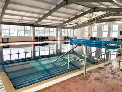 a large swimming pool with a blue railing in a building at The Retreat Lodge in Newquay