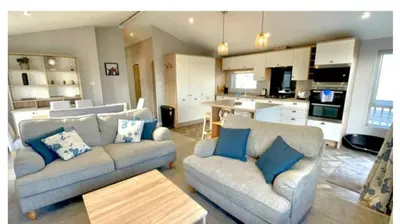 a living room with two couches and a kitchen at The Retreat Lodge in Newquay