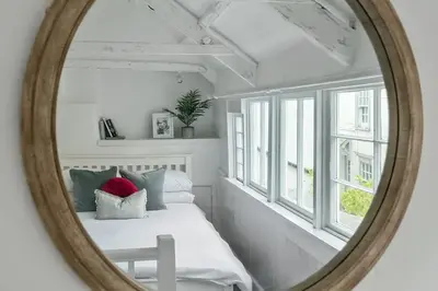 a mirror reflecting a bedroom with a bed and a window at Moll's Yard in Port Isaac