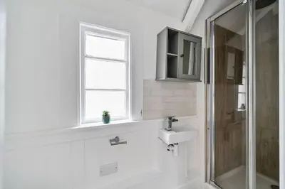 a white bathroom with a sink and a shower at Moll's Yard in Port Isaac