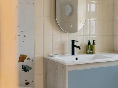 a bathroom sink with a mirror and bottles on it at Rose Garden Maisonette in Falmouth