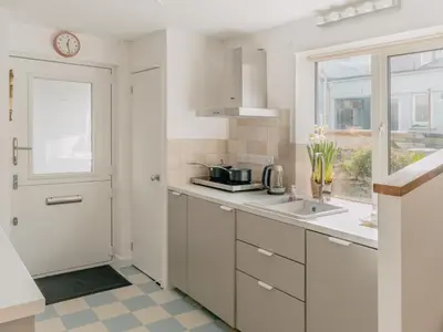 a white kitchen with a sink and a window at Rose Garden Maisonette in Falmouth