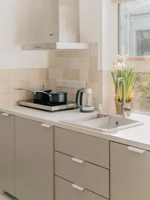 a white kitchen with a sink and a window at Rose Garden Maisonette in Falmouth