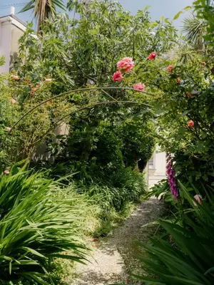 a garden path with pink flowers and plants at Rose Garden Maisonette in Falmouth