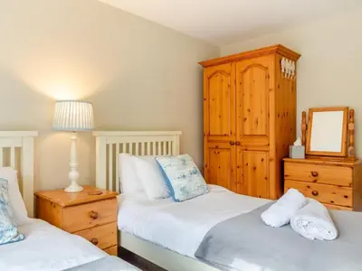 a bedroom with two beds and a wooden cabinet at 3 Bed in St. Austell oc-95623 in Gorran Haven