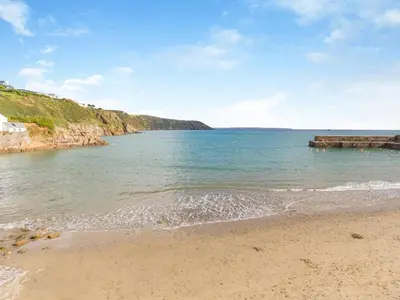 a beach with a wooden pier in the water at 3 Bed in St. Austell oc-95623 in Gorran Haven