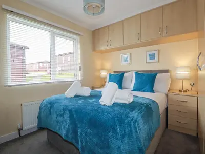 a bedroom with a large bed with blue and white sheets at Laurel Lodge in Tintagel